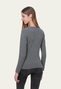 Pull gris à manches longues avec un col rond, en matière tricotée douce. Coupe ajustée et texture lisse, vu de dos.