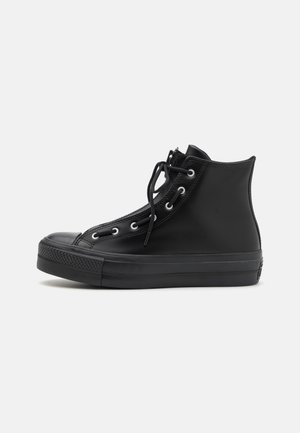 Black high-top sneakers made of smooth rubber with a textured toe cap, eyelet accents, and a front zipper with laces.