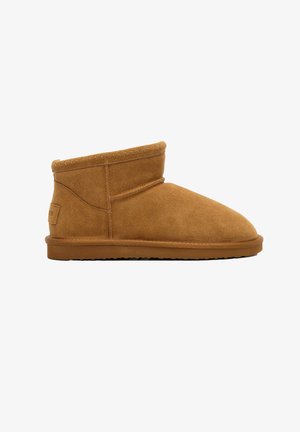 Brown suede ankle boot with a rounded toe, soft texture, and a folded upper section. Flat rubber sole with a simple, understated design.
