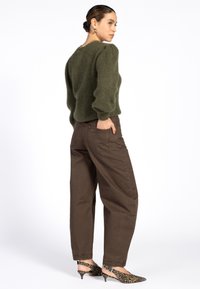 Olijfgroene, fluffy trui met pofmouwen, gecombineerd met bruin, hoog-geknoopte broek en slingback hakken met luipaardprint.