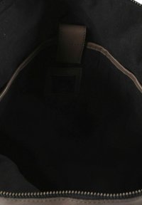 Interieur van een bruine leren handtas met zwarte stoffen voering, voorzien van een ritssluiting en een klein vakje aan de binnenkant voor organisatie.