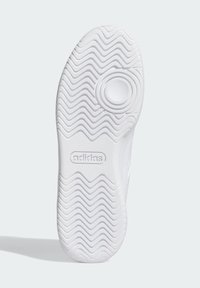 Vit gummisula med ett zickzack-mönster och rundad central detalj; har präglad branding och en slät yta.