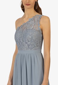 Himmelblaues Kleid mit einem schulterfreien Design. Das Oberteil verfügt über komplizierte Spitzenverzierungen, während der Rock plissiert ist, um zusätzliche Textur zu verleihen.