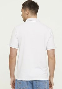 Witte polo shirt met korte mouwen, voorzien van een klassieke kraag en blauwe accenten op de mouwzoom. Glad textiel.
