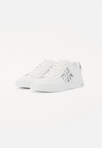 Sneakers in tela bianca con design a lacci, suola testurizzata e dettagli stampati sul lato. Presentano una forma bassa e una punta rinforzata.