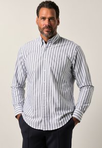 Camicia a righe grigia e bianca con colletto, maniche lunghe e orlo arrotondato. Logo sottile sul petto. Tessuto morbido.