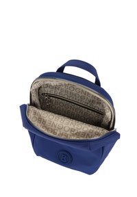 Blå läderryggsäck med dragkedjestängning. Inuti klädd med beige tyg som har ett upprepat logomönster. En dragkedjeficka inuti.