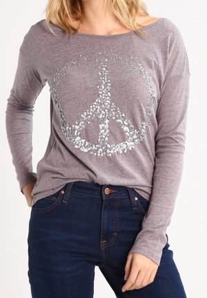 Grå langærmet skjorte med et stort palietfredssymbolgrafik i midten. Stoffet er blødt; skjorten har en afslappet pasform og bådudskæring.