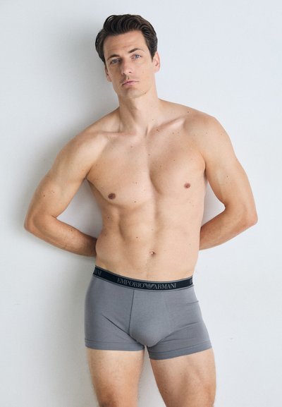 Sive muške bokserice s crnim pojasom "Emporio Armani", izrađene od glatkog, rastezljivog materijala, koja se čvrsto prilagođava struku i bedrima.
