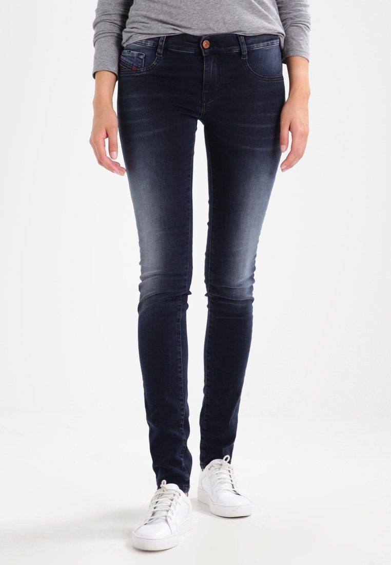 Úzké džíny z tmavě modrého denimu s vybledlým předním dílem, klasickým pětikapsovým designem a zapínáním na jeden knoflík. Kombinovány s bílými teniskami.