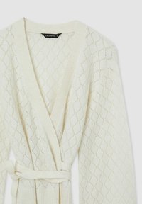 Cardigan aperto color crema con un motivo a rombi, tessuto a maglia testurizzata, maniche lunghe e una cintura abbinata in vita.