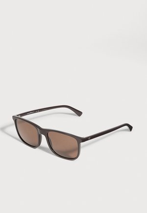 Lunettes de soleil rectangulaires brun foncé, aux verres teintés bruns, présentées ouvertes sur un fond clair.