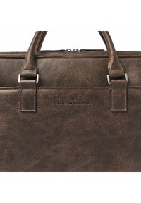 Gros plan d'une mallette en cuir brun foncé avec poignées cousues et poche avant, arborant le logo embossé "Castelijn & Beerens".