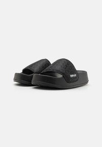 Sandales noires à semelle plate avec une tige en mesh, dotées d'une large sangle et d'une semelle texturée. Des bords renforcés et un accent logo sont visibles.