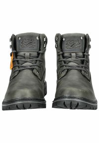 Bottes en cuir vert foncé avec une semelle robuste, des œillets en métal et des lacets noirs. Elles présentent une étiquette orange et un logo en relief sur la languette.