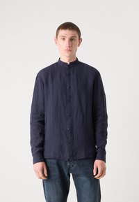 Marineblå linne skjorte med mandarin krage, lange ermer og knappestolpe foran. Teksturert stoff og avslappet passform. Brukt med denimjeans.