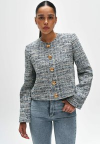 Blazer gemaakt van een gestructureerde geweven stof in blauw en witte tinten met vijf goudkleurige knopen, ronde hals en lange mouwen.