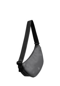 Sac bandoulier en tissu gris foncé, de forme courbe avec une texture lisse. Il dispose d'une sangle noire réglable et d'un détail de marque minimal.