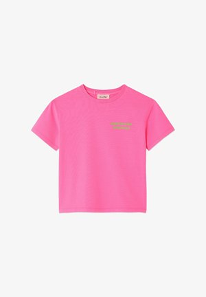 Dziecko o kręconych włosach, ubrane w jaskraworóżowy T-shirt z napisem "AMERICAN VINTAGE" na plecach oraz jasnoszare spodnie, stojące w pomieszczeniu.