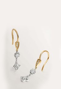 Pendientes en oro y plata con pequeños diamantes, que presentan un gancho de oro y elaborados charms colgantes en forma de corazón de plata.