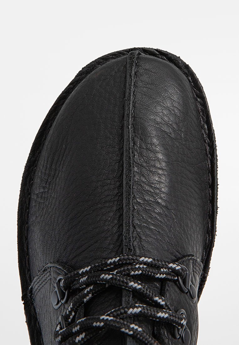 Chaussure en cuir noir avec une finition texturée, bout rond et système de laçage. Dispose de coutures contrastantes et d'une semelle robuste.