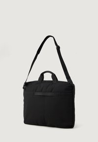 Czarna torba na laptopa z teksturowanej tkaniny, z podwójnymi uchwytami i regulowanym, odczepianym paskiem na ramię. Prosty design z zamkiem błyskawicznym i tylną kieszenią.