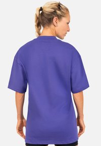 Paarse oversized t-shirt met korte mouwen, ronde hals en een gestructureerde stof. Schone ontwerp zonder zichtbare logo's of patronen.