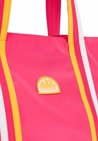 Borsa a tracolla rosa con accenti a strisce gialle e bianche. Presenta un logo giallo circolare con un design a onda. Materiale liscio e lucido.