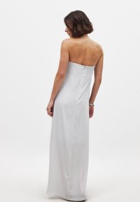 Robe de soirée sans bretelles, longue jusqu'au sol, en satin gris clair ; silhouette épurée avec un dos droit, texture lisse et détails minimaux.