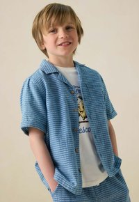 Hellblau gestreift kurzärmliges Hemd mit einer Brusttasche, kombiniert mit einem weißen T-Shirt mit grafischem Druck. Mit Knopfleiste vorne, lässige Passform.