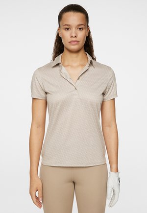 Beige polo t-shirt med et subtilt mønsterdesign, korte ærmer og krave. Har knapper ved halsen. Følger med en hvid golfhandske.