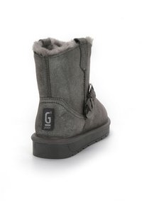 Grå mocka ankelsko med fuskpälsfoder, med en spänne-accent, texturerad yta och en gummisula för grepp och stabilitet.