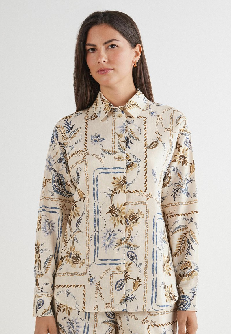 Chemise à boutons à motif floral beige clair, ornée d'accents bleus et marron, avec un col classique et des manches longues.