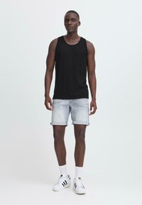 Svart bomullstopp, lyseblå denimshorts med oppbrettede ermer, hvite sokker og svart-hvite sneakers. Enkelt design, avslappet utseende.