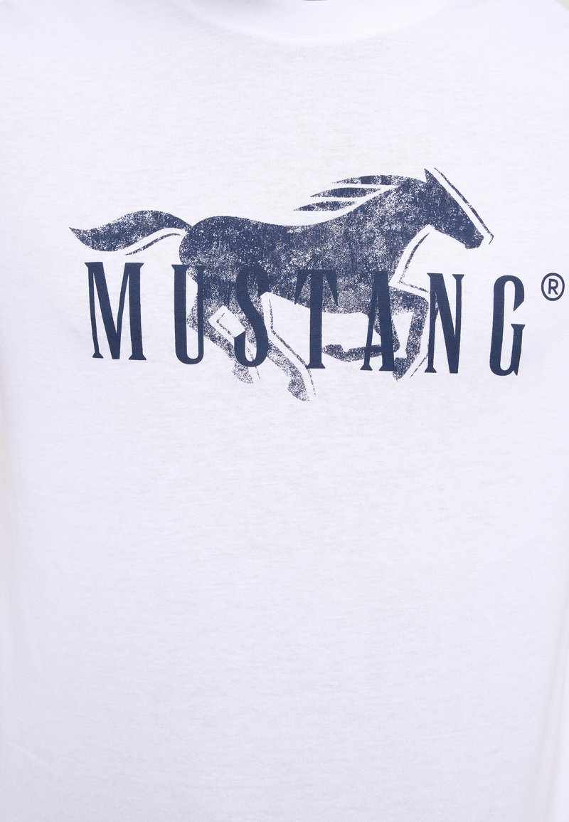 T-shirt blanc avec un graphique de silhouette de cheval navy et le texte "MUSTANG" en foncé en dessous, fabriqué en coton doux.
