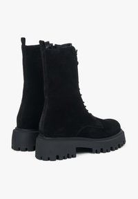 Czarne zamszowe botki za kostkę z masywną gumową podeszwą, sznurowanym zapięciem i wzmocnionym obcasem. Teksturowane wykończenie o matowym wyglądzie.