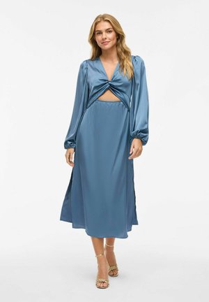 Satin midi obleka v mehki modri barvi z zavojem spredaj, dolgimi puhastimi rokavi, stranskimi razporki in nabranim pasom. Ujemajoča se z zlatimi sandali na trakove.
