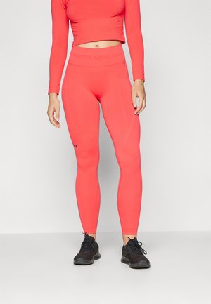 Lys korallfarget langermet topp med kort skjæring, kombinert med matchende høy midje leggings. Slank passform, elastisk stoff og logo på midjen. Sorte treningssko.