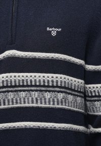 Granatowy dziergany sweter z białymi geometrycznymi paskami na klatce piersiowej i częściowym zamkiem błyskawicznym, z małym haftowanym logo Barbour.