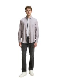 Chemise légère en violet clair à manches longues avec un design à bouton, associée à un jean gris foncé et des baskets blanches. Texture lisse, coupe décontractée.