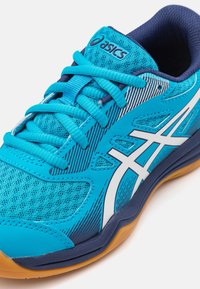 Sininen urheilujalkine, joka on valmistettu verkko- ja synteettisistä materiaaleista. Varusteena valkoisia yksityiskohtia, teksturoituja kuvioita ja kuminen pohja.