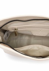 Interiér béžové kožené kabelky, obsahující zipovou kapsu, hladkou podšívku a kontrastní černý zip. Obsahuje značkovou visačku.