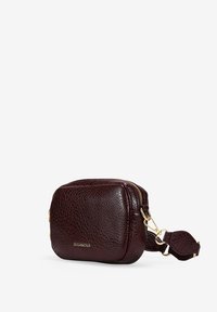 Bolso cruzado de cuero texturizado marrón oscuro con cremallera y herrajes dorados, correa desmontable y logo "BOSANOVA" en el frente.