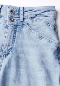 Jasnoniebieskie dżinsy z lekko wyblakłym wykończeniem. Posiadają dwa metalowe zapięcia na guziki oraz kontrastowe szwy wzdłuż szwów.