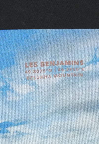 Tessuto multicolore con un cielo blu e nuvole, e testo arancione: "LES BENJAMINS", coordinate e "MONTE BELUKHA."