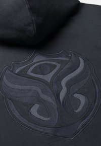 Black hoodie featuring a textured, dark gray embroidered logo with abstract design elements shaped like a crest or emblem.