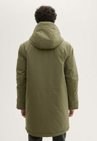 Giacca parka verde oliva con cappuccio, caratterizzata da una texture liscia e un orlo leggermente allungato. Nessuna ferramenta o modello visibile.