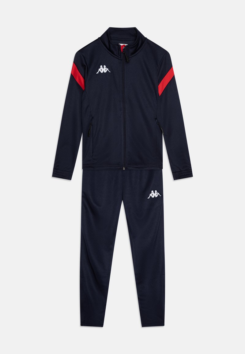 Jūrinis sportinis kostiumas, kuriame yra užtrauktuku užsegamas švarkas su raudonomis juostelėmis ir siuvinėtu logotipu, derinamas su atitinkamomis kelnėmis. Sklandus, lengvas audinys.