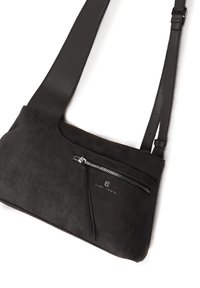 Piccola borsa a tracolla nera in suede con una tracolla in pelle liscia, dotata di una tasca frontale con zip e un sottile dettaglio del logo.