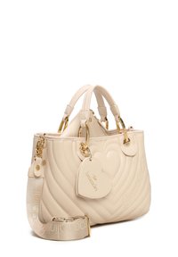 Borsa a tracolla trapuntata beige con hardware dorato, manici doppi e tracolla removibile. Presenta un'etichetta a forma di cuore e logo impresso.